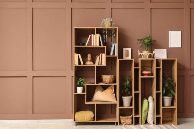 Kitaplı, dekorlu ve kahverengi duvarlı ahşap raf ünitesi.