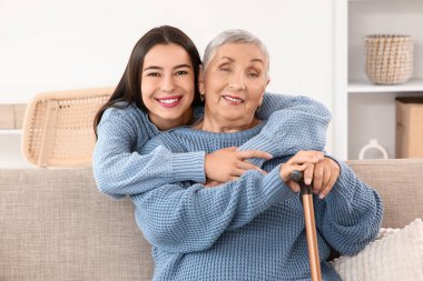 Mutlu genç bir kadın, büyükannesine sopayla sarılıyor.