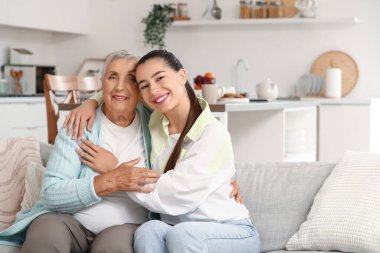 Büyükannesiyle kanepede kucaklaşan genç bir kadın.