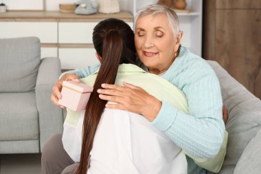 Torununa evde kanepede sarılan son sınıf öğrencisi bir kadın.