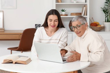 Masada dizüstü bilgisayar kullanan büyükannesi olan genç bir kadın.