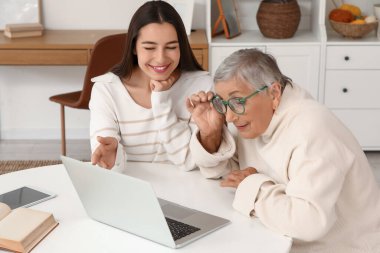 Masada dizüstü bilgisayar kullanan büyükannesi olan genç bir kadın.