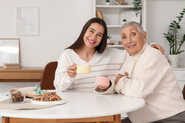 Büyükannesiyle birlikte masada çay içen genç bir kadın.