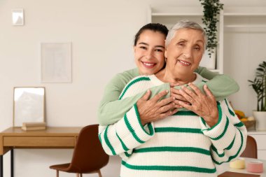 Mutlu genç bir kadın büyükannesine sarılıyor.