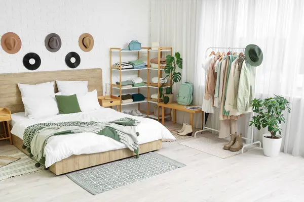 Rahat bir yatak, raflar ve yatak odasının iç kısımlarında giysi.