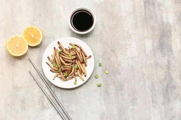 Bir tabak yeşil soğanlı, limonlu ve arka planda soya soslu kızarmış kurtçuk.