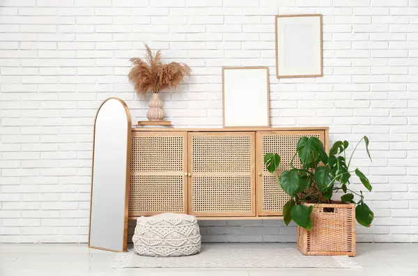 Çekmeceli modern odanın içi ve beyaz tuğla duvarın yanındaki Monstera bitkisi.