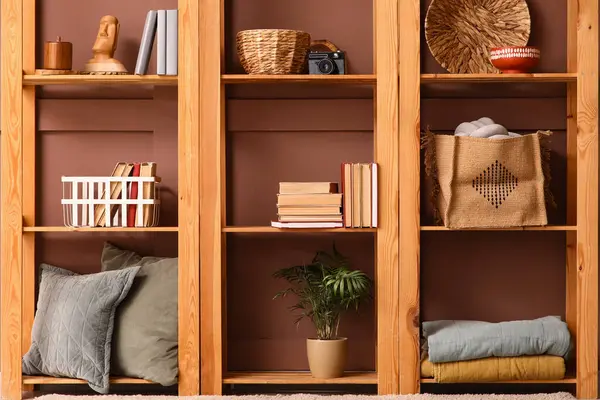 Kitaplı ahşap raf ünitesi ve kahverengi duvarın yanında şık dekorlar.