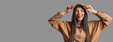 Gri arka planda dili gösteren günlük kıyafetli havalı genç bir kadın. Mesaj için yeri var.