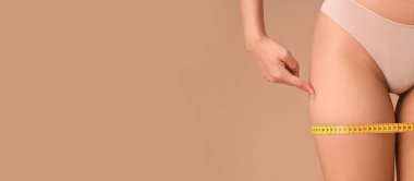 Vücudunda çatlaklar ve bej arkaplan ile ölçüm bandı olan güzel genç bir kadın.