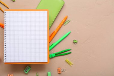 Boş defter ve bej arkaplanda farklı kırtasiye malzemesi