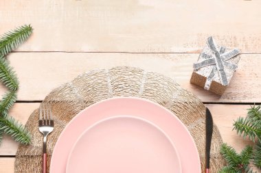 Köknar dalları, hediye kutusu ve bej ahşap arka planda çatal bıçaklı şenlik masası.