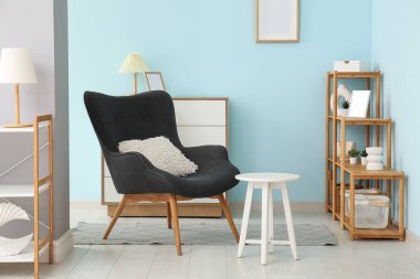 Gri kanepeli, raf üniteli ve taburesi olan oturma odasının içinde.