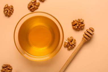 Bej arka planda ceviz ve dipli bir kase tatlı bal.