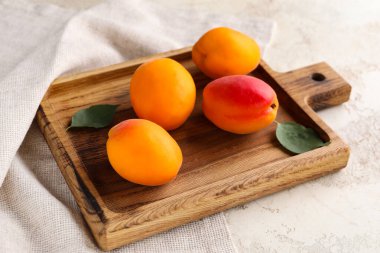 Beyaz arka planda tatlı kayısıları olan ahşap tahta.