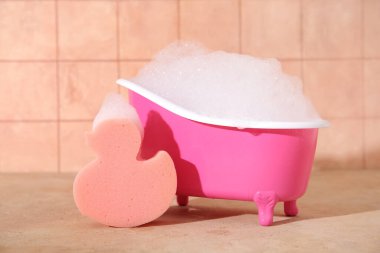 Sabun köpüğü ve süngerli küçük bir küvet.