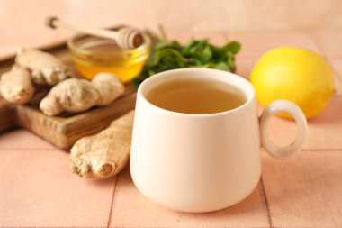 Bir fincan zencefilli çay ve bal ile pembe fayans masasında.