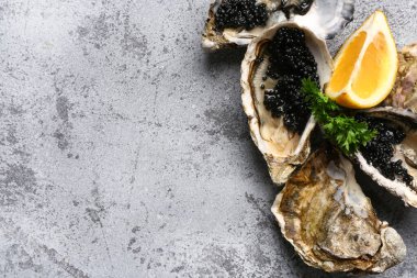 Limonlu lezzetli istiridyeler ve gri arka planda siyah havyar.