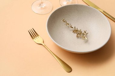 Bej masa üzerinde altın yapraklar ve çatal bıçak takımı olan zarif bir masa.