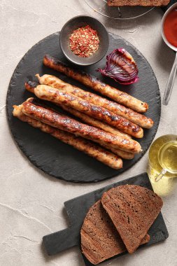 Lezzetli ızgara sosis ve gri arka planda ekmek.