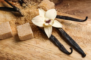 Aromatik vanilya şekeri, çiçek ve tahta zemin üzerinde çubuklar