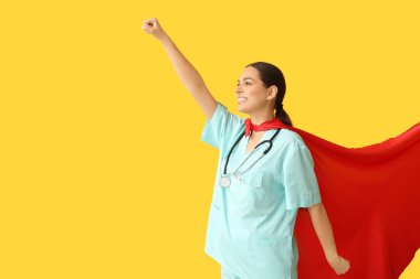 Sarı arka planda süper kahraman kostümlü güzel bayan doktor.