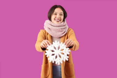 Mor arka planda kar taneleri olan, sıcak eşarplı, güzel, Asyalı bir kadın.