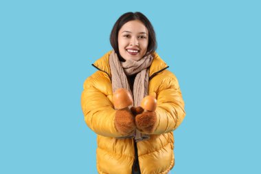 Mavi arka planda dekoratif mantarları olan sıcak eşarplı güzel Asyalı bir kadın.