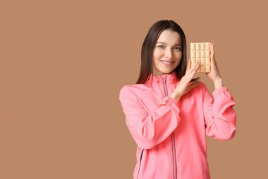 Kahverengi arka planda beyaz çikolatalı genç bir kadın.