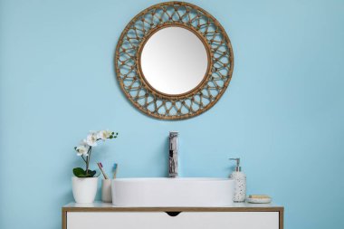 Banyoda mavi duvarın yanında banyo malzemeleri olan modern lavabo.