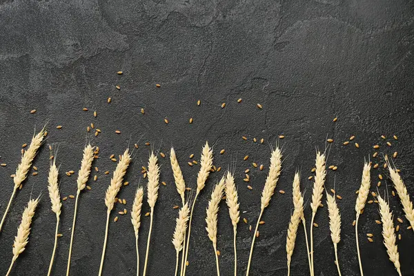 Buğday kulakları ve tahıllar siyah grunge masasında