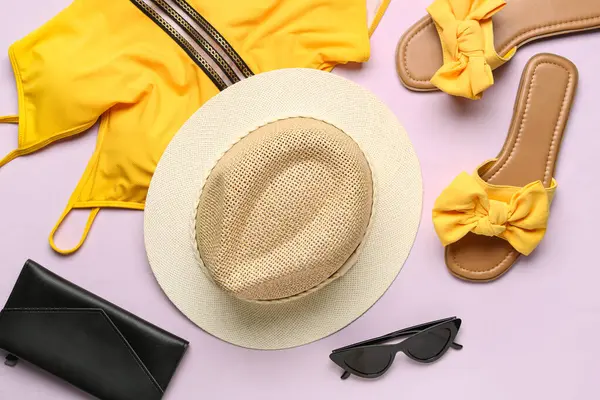 Şık plaj aksesuarları ve leylak arka planda mayo.