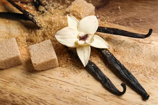 Aromatik vanilya şekeri, çiçek ve tahta zemin üzerinde çubuklar