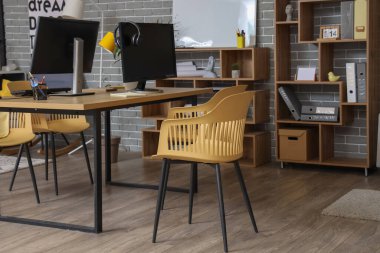 Çalışma yeri ve raf üniteleri olan şık bir ofis.