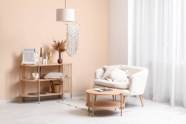 Yastıklı rahat bir kanepe ve oturma odasının iç tarafındaki pencereye yakın dekorlu ahşap raf ünitesi.