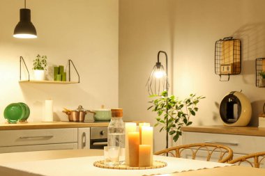 Parlayan lambaları, beyaz tezgahları, mumları ve akşam masası olan modern mutfağın içi.