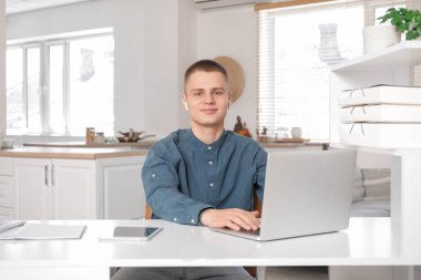 Açık ev ofisinde dizüstü bilgisayarla çalışan genç bir serbest çalışan.