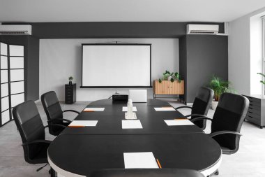 Masa ve projektör ekranlı konferans salonunun içi