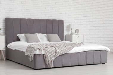 Yatak, lamba, yastık ve komodinli rahat bir yatak odası.