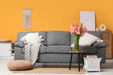 Kanepe ve vazoda gladyatör çiçekleri olan şık bir oturma odası.