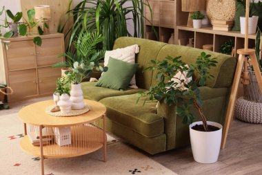 Oturma odasının içinde yeşil kanepe, masa ve bitkiler.