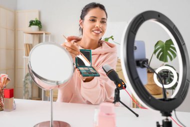 Female beauty blogger with eyeshadows recording video at home