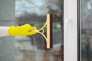 Odada cam sileceği olan erkek işçi, yakın plan.