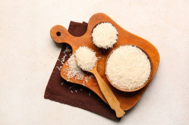 Beyaz zemin üzerinde çiğ pirinç olan kâseler ve tahta kaşık.