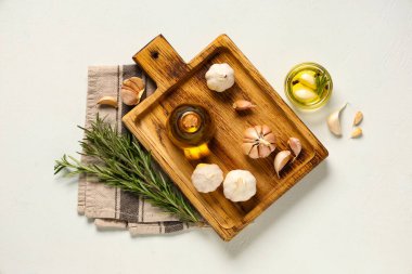 Beyaz arka planda biberiyeli taze sarımsak yağı şişesi ve cam kase.