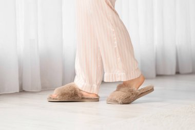 Kahverengi terlikli genç bir kadın evinin penceresinin yanında yürüyor, yakın plan.