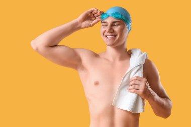 Sarı arka planda havlusu olan erkek yüzücü