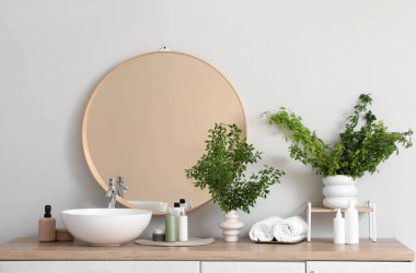 Lavabonun yanında yeşil dalları olan bir banyo.