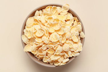 Bej arka planda lezzetli mısır gevrekleri olan kase, yakın plan.