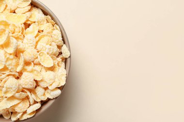 Bej arka planda lezzetli mısır gevrekleri olan kase, yakın plan.